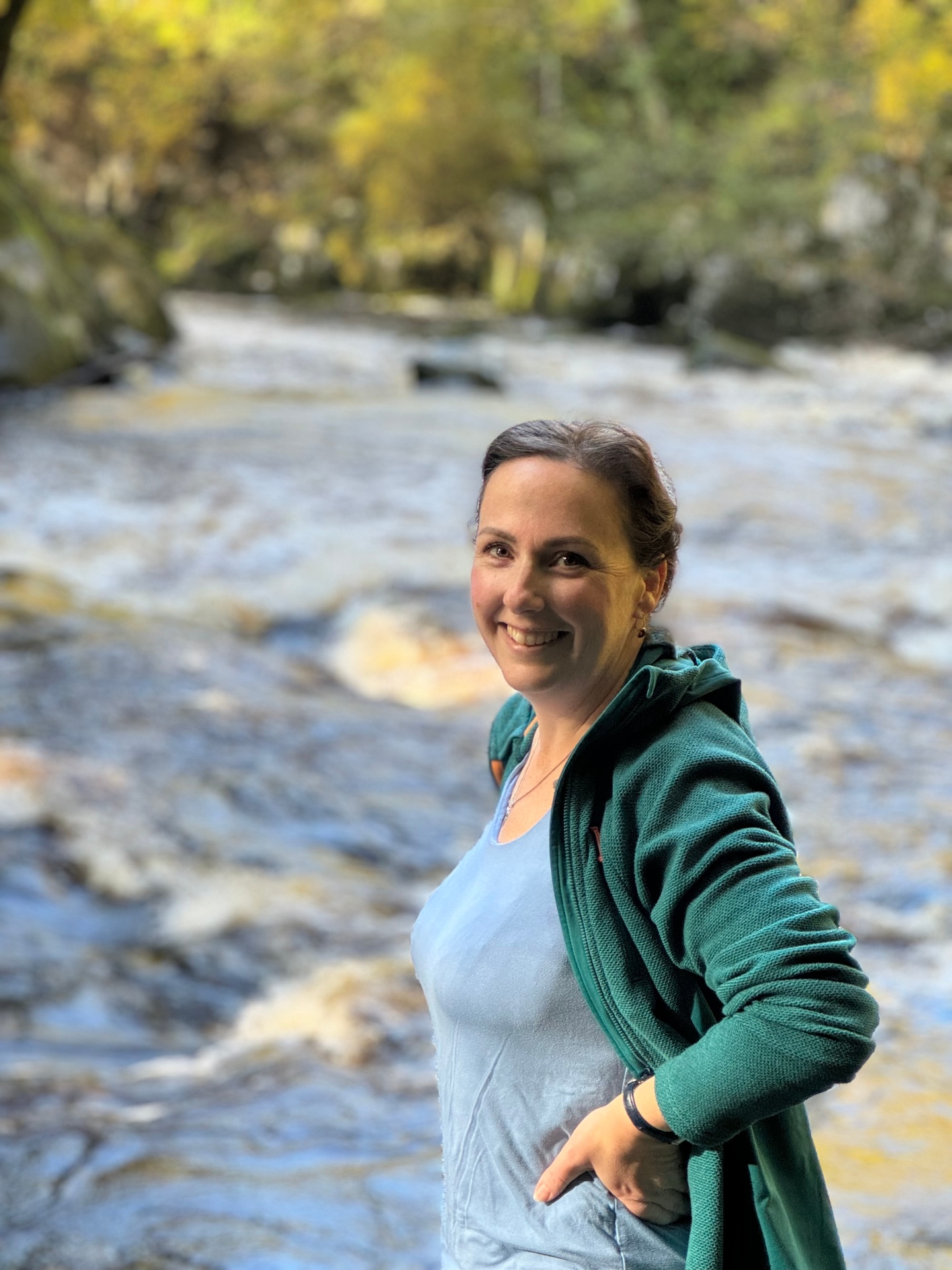 Coralie, founder of Pause & Prepare, smiling outdoors by a river